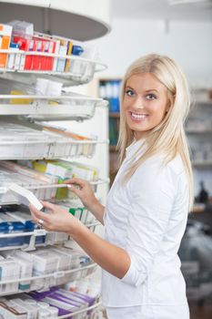Portrait of woman standing in pharmacy drugstore holding medication box