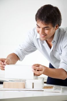 Young male architect preparing a model house on desk