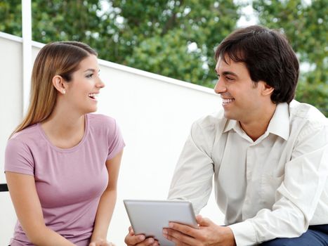 Young male with tablet PC smiling while looking at female