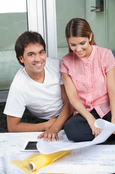 Portrait of young man smiling with woman looking at house plans