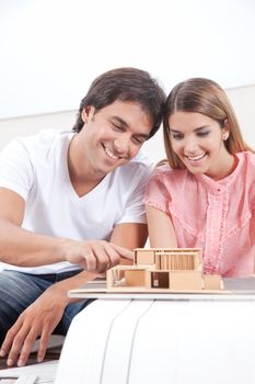 Happy young couple looking at house model .