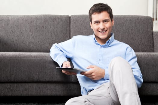 Young man holding digital tablet at home .