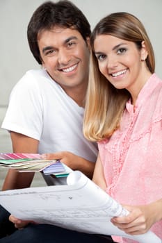Portrait of happy young couple with blueprint and color swatches