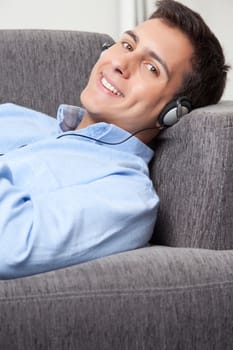 Relaxed young man on couch listening music.
