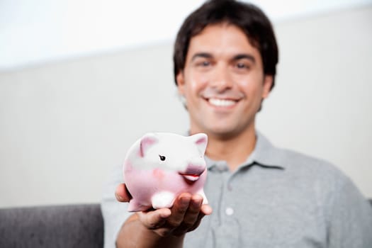 Happy young man holding piggy bank.