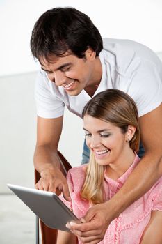 Happy young man showing something to woman on tablet PC
