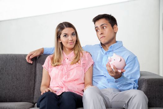 Portrait of young woman smiling while man holding piggybank