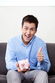 Man with piggy bank showing thumb up sign.