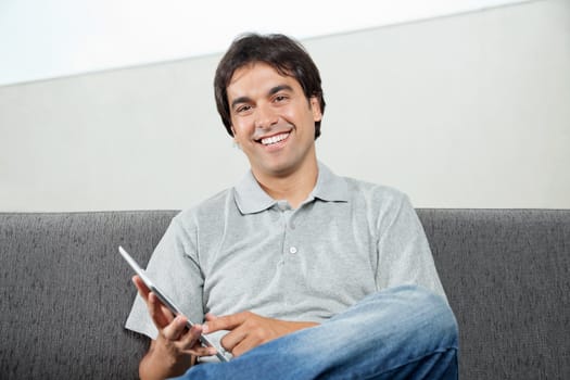 Portrait of happy young man in casual wear using digital tablet