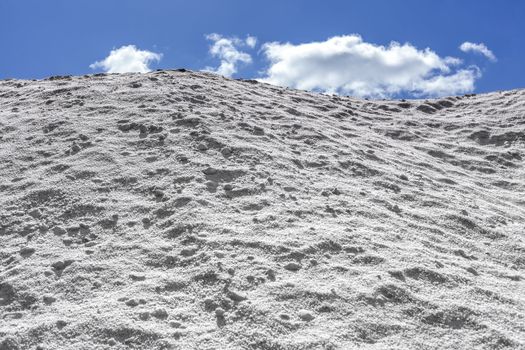 Big pile of freshly mined salt, set against a blue sky