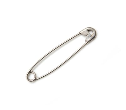Closed safety pin. Cut out, on white background. Macro. On edge 