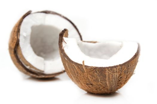 Closeup of cracked coconut on white background with light shadow. Shallow focus depth on front coconut 