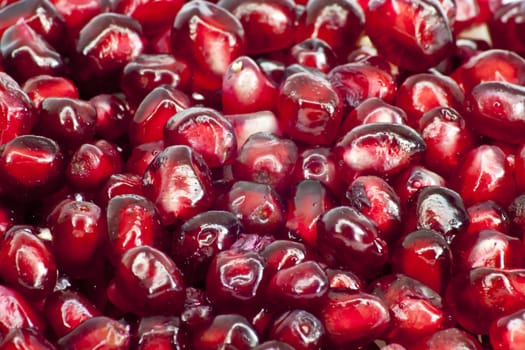 Extreme close up background of a red juicy ripe pomegranate fruit seeds 