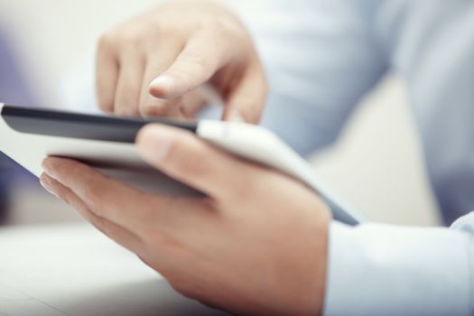 Hands of businessman using tablet PC at office