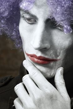 Single sad funny man with theatrical makeup and wig. Vertical photo with dramatic colors and toning