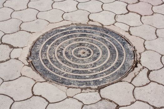 Cast iron manhole cover is inset into old brick street paving 