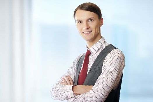Smiling businessman with arms crossed in his office