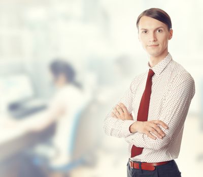 Young businessman stands in defocused office. Color photo