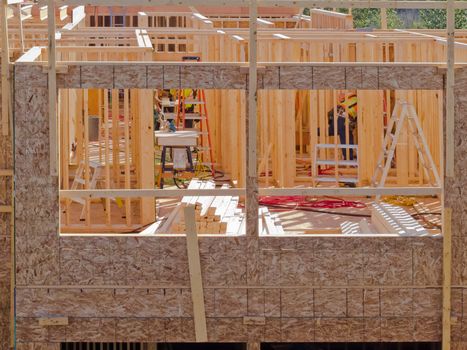 Exterior view of new home construction which still has no roof so interior wooden framing structure is visible in detail