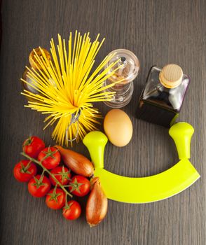 Typical Italian spaghetti and other ingredients over wooden background