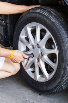Replacing lug nuts by hand while changing tires on a vehicle.