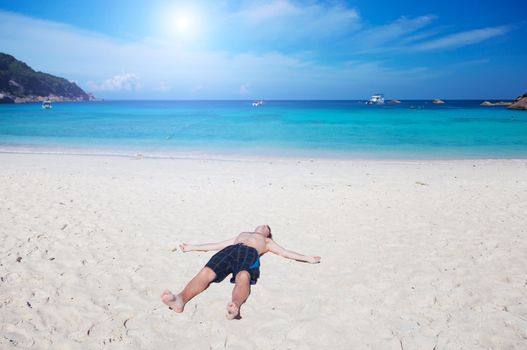 Man lies on a beach on an ocean coast