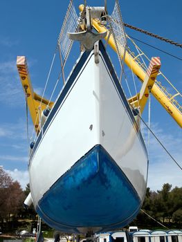 sailboat hanging on crane and preparing for service