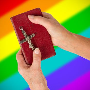 Old hands (woman) holding a very old bible, rainbow flag pattern