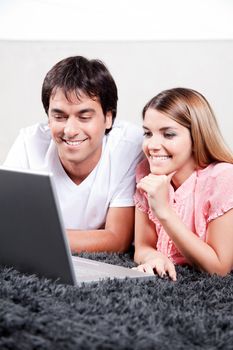 Happy young couple using laptop.
