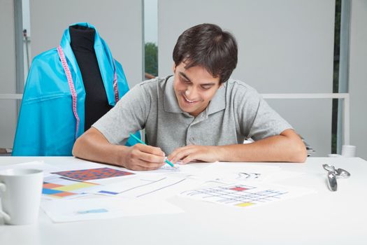 Young male designer drafting new designs on paper at workshop