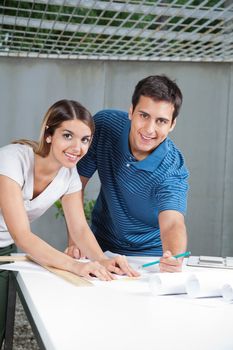 Portrait of young architects working on blueprints together