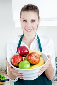 Pretty blond female holding bowl with a smile in kitchen