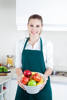 Pretty young woman with bowl of apples and bananas in kitchen