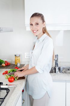 Blond female woman cutting vegetables in kitchen