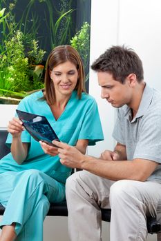 Female dentist showing dental X-ray report to serious patient in clinic