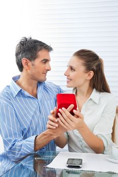 Middle aged man making proposal of marriage to beautiful woman while sitting at table