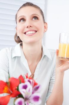 Young woman holding glass of juice, dreaming.