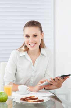 Young woman having healthy breakfast holding digital tablet.