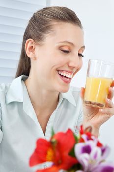 Happy young businesswoman holding glass of orange juice