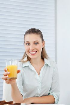 Portrait of a friendly young businesswoman holding glass of orange juice