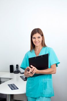 Portrait of a happy female dentist holding clipboard in dental clinic