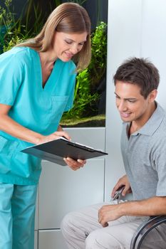 Female dentist taking an appointment of male patient on clipboard at clinic