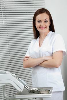 Portrait of happy confident female dentist standing with arms crossed in clinic