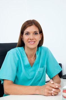 Portrait of mid adult female dentist smiling at desk