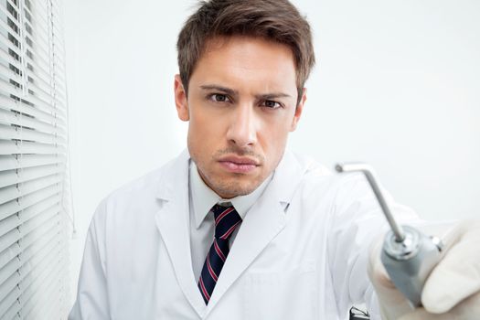 Portrait of young male dentist holding water spraying tool