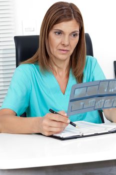 Female dentist analyzing dental X-ray report at office desk