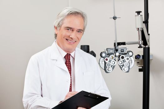 Experienced optometrist smiling with notepad in his clinic