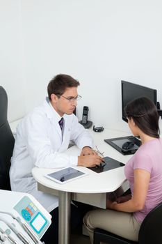 Young male dentist showing dental X-ray report to patient in clinic