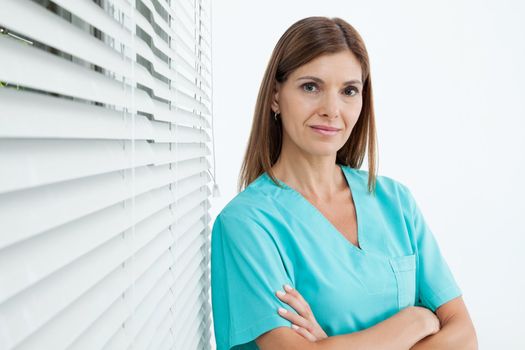 Portrait of confident female dentist standing with arms crossed in clinic