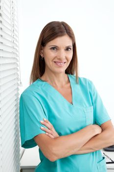 Portrait of confident female dentist standing with arms crossed in clinic